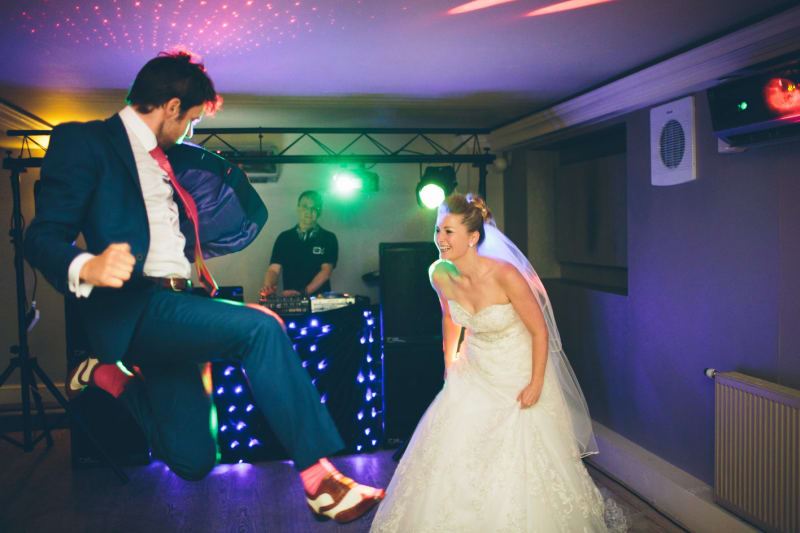 Bridebook.co.uk- groom jumps on dance floor as bride laughs