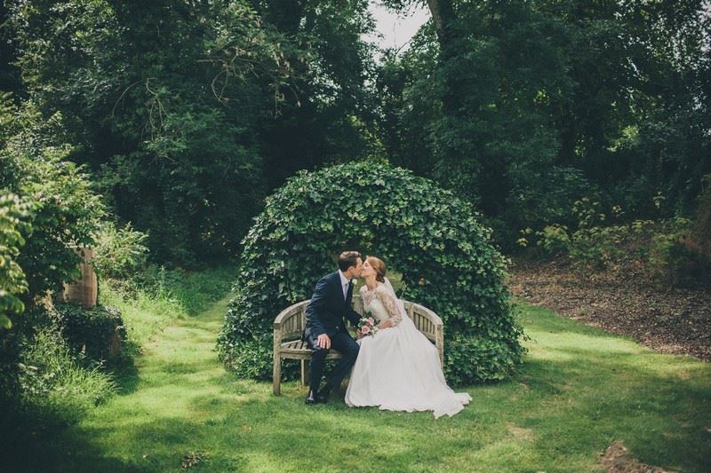 Bridebook.co.uk- bride and groom kissing under green arch