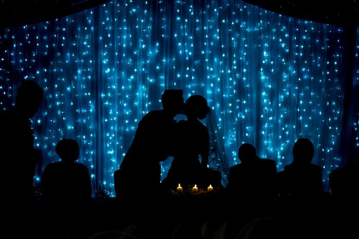 Brautpaar küsst sich mit Lichtern im Hintergrund