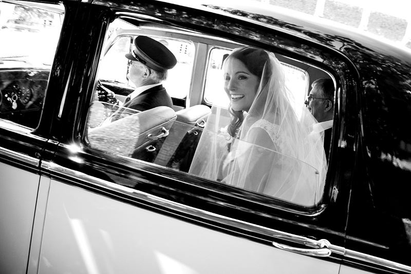 Bridebook.co.uk- bride smiling from inside of wedding car