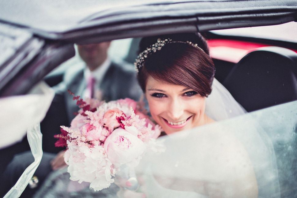 Braut lächelt aus dem Hochzeitsauto