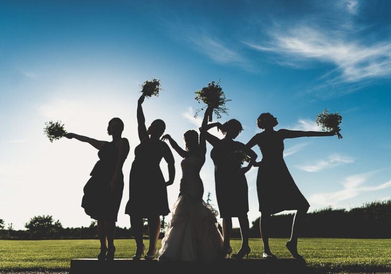 Bridebook.co.uk- bride and bridesmaids silhouetted against the sun holding up their bouquets