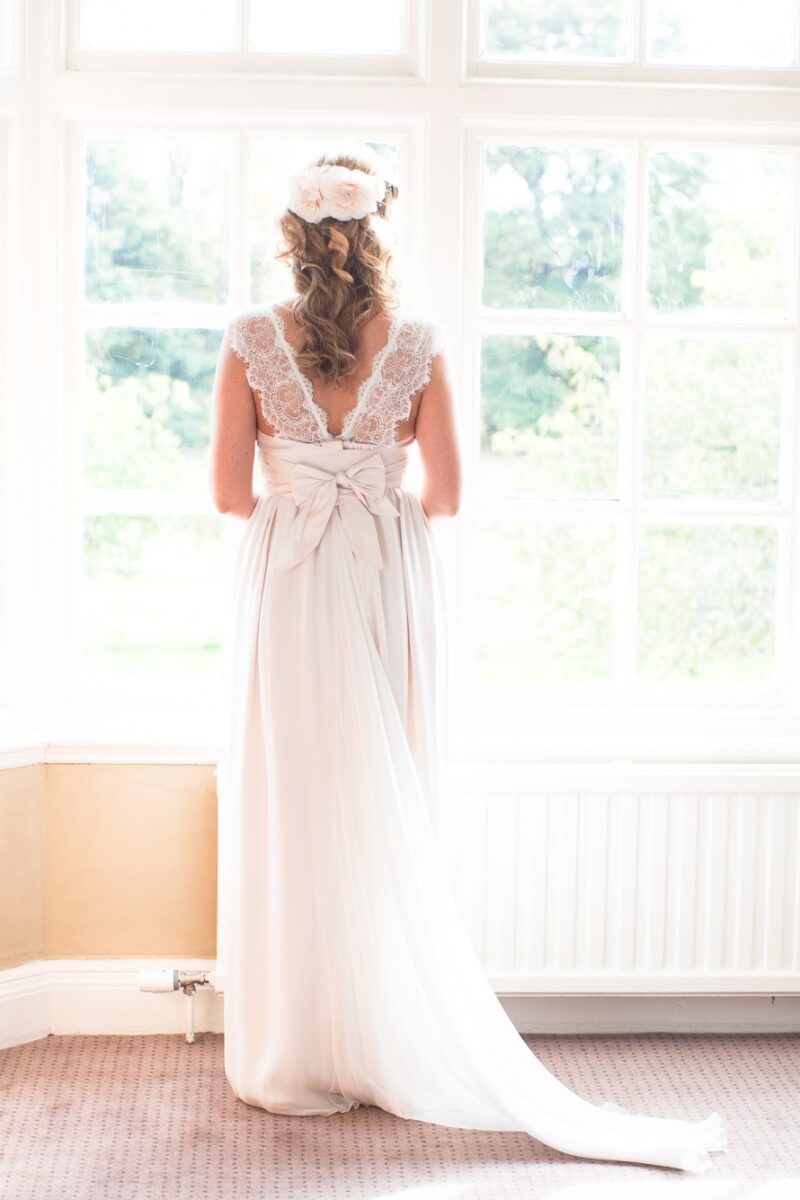  bride in her gown facing the window