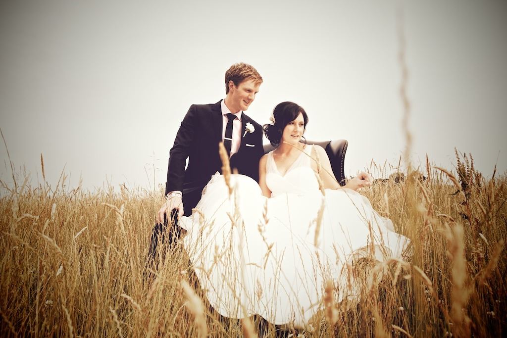 Braut und Bräutigam in einem Sessel auf einem Feld
