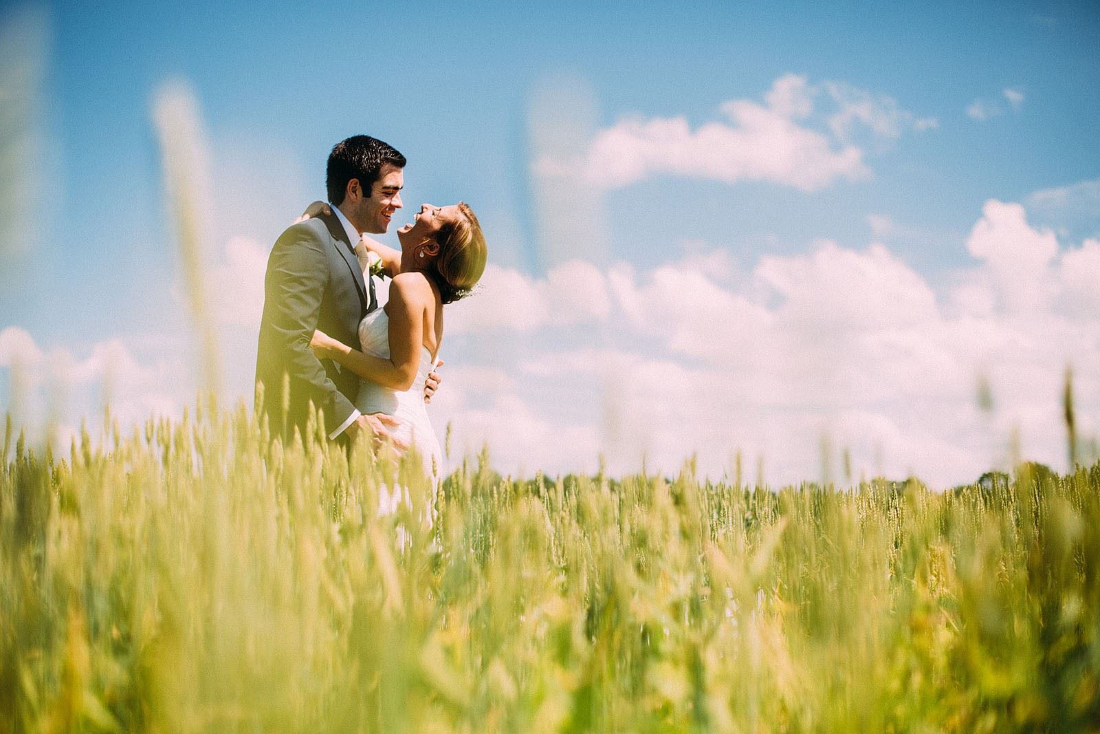 Braut und Bräutigam umarmen und lachen auf einem Feld