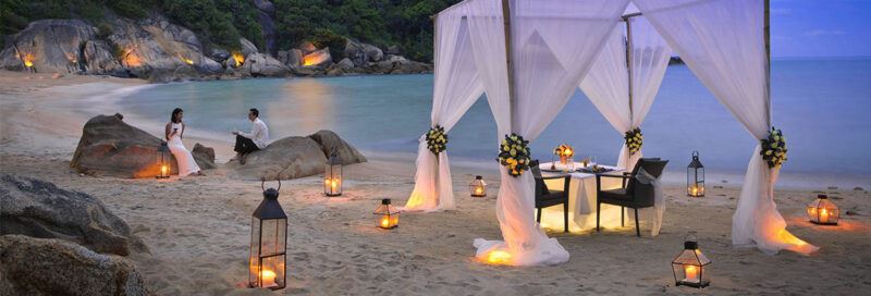 Bridebook.co.uk- bride and groom having romantic dinner on beach