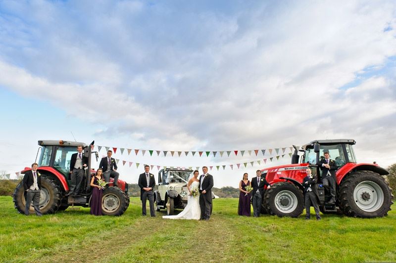 Bridebook.co.uk- bride groom and wedding party next to tractors