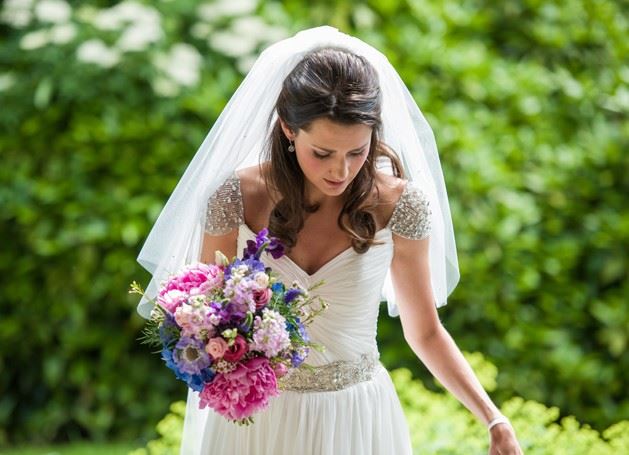 Bridebook.co.uk- bride in an embellished dress holding her bouquet