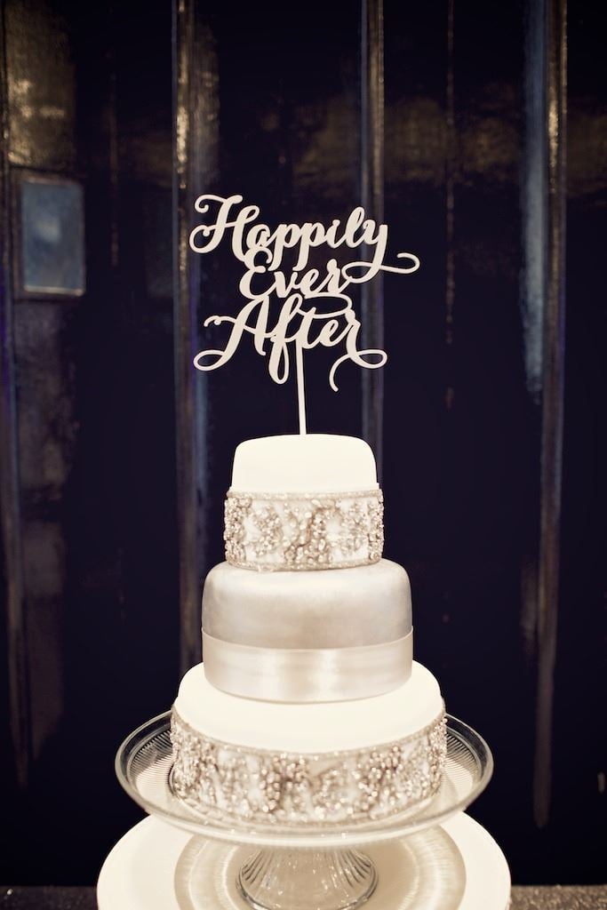 Bridebook.co.uk- white cake with metallic accents and a happily ever after topper