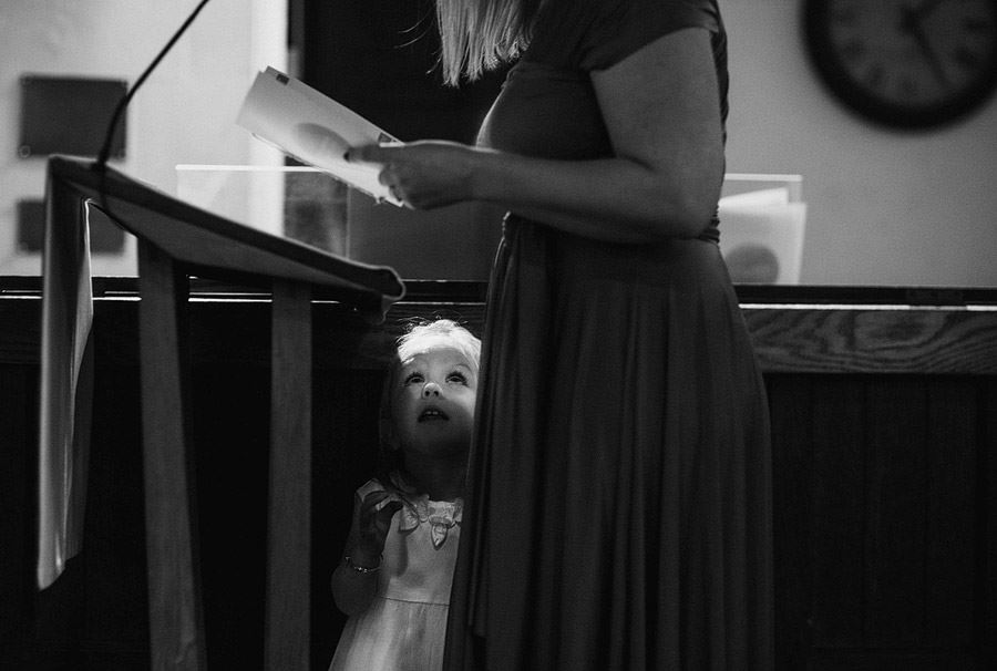 Bridebook.co.uk flowergirl looks up at mum doing church reading