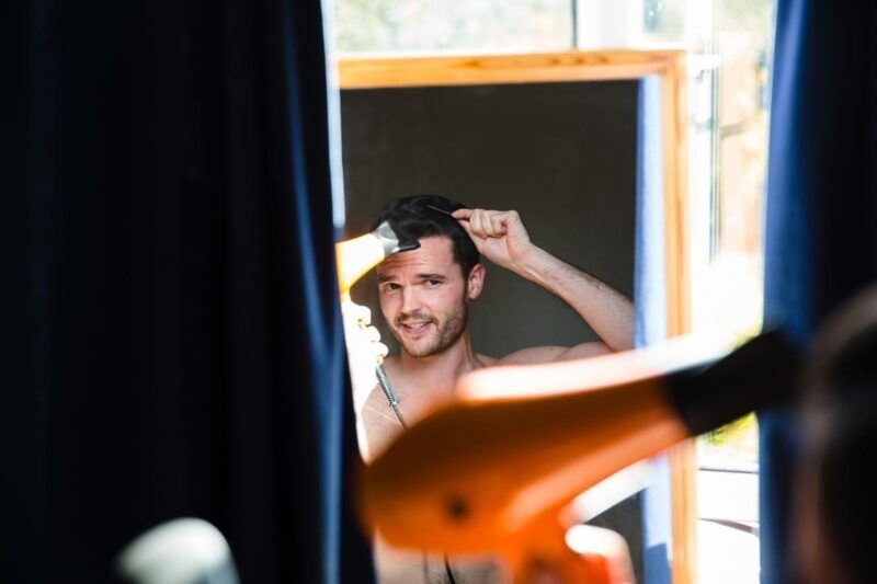 Bridebook.co.uk- groom blow drying his hair in the mirror