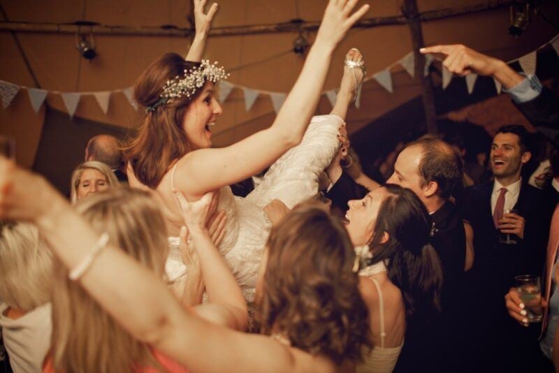 Bridebook.co.uk- bride being lifted up by the guests during reception