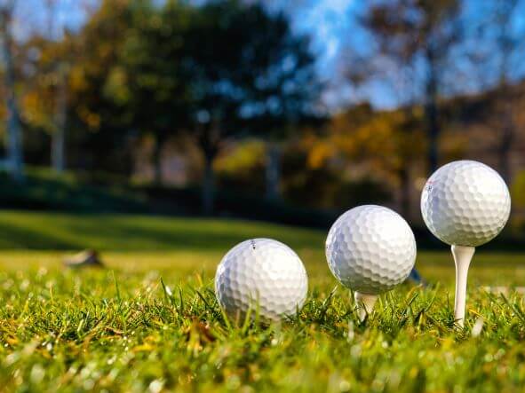 Three golf balls set up on the grass