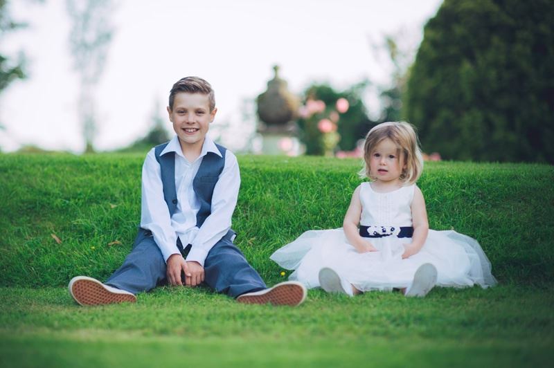 Bridebook.co.uk- page boy and flower girl sitting on grass