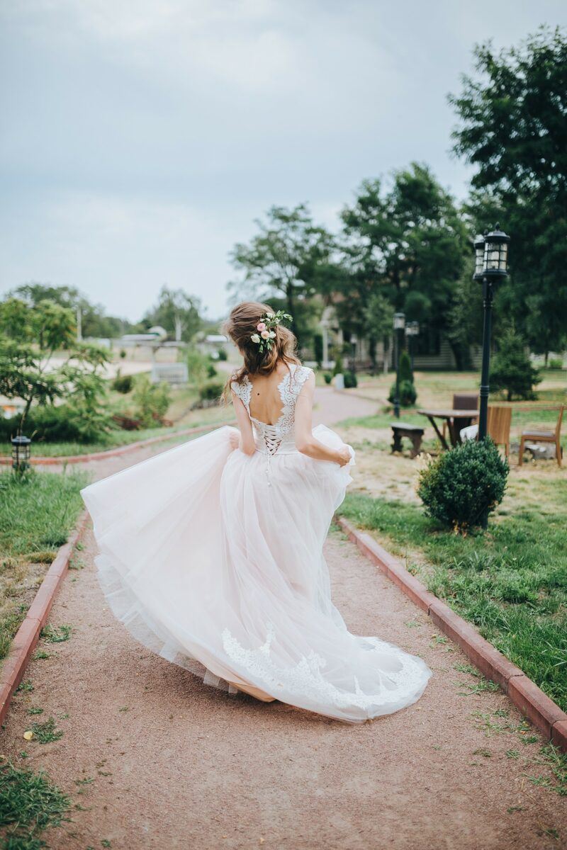 bridebook.co.uk bride running through garden in wedding dress with lace trim