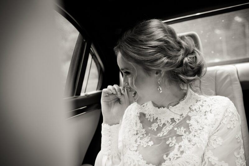 Bridebook.co.uk bride in car in high neck wedding dress and jewellery