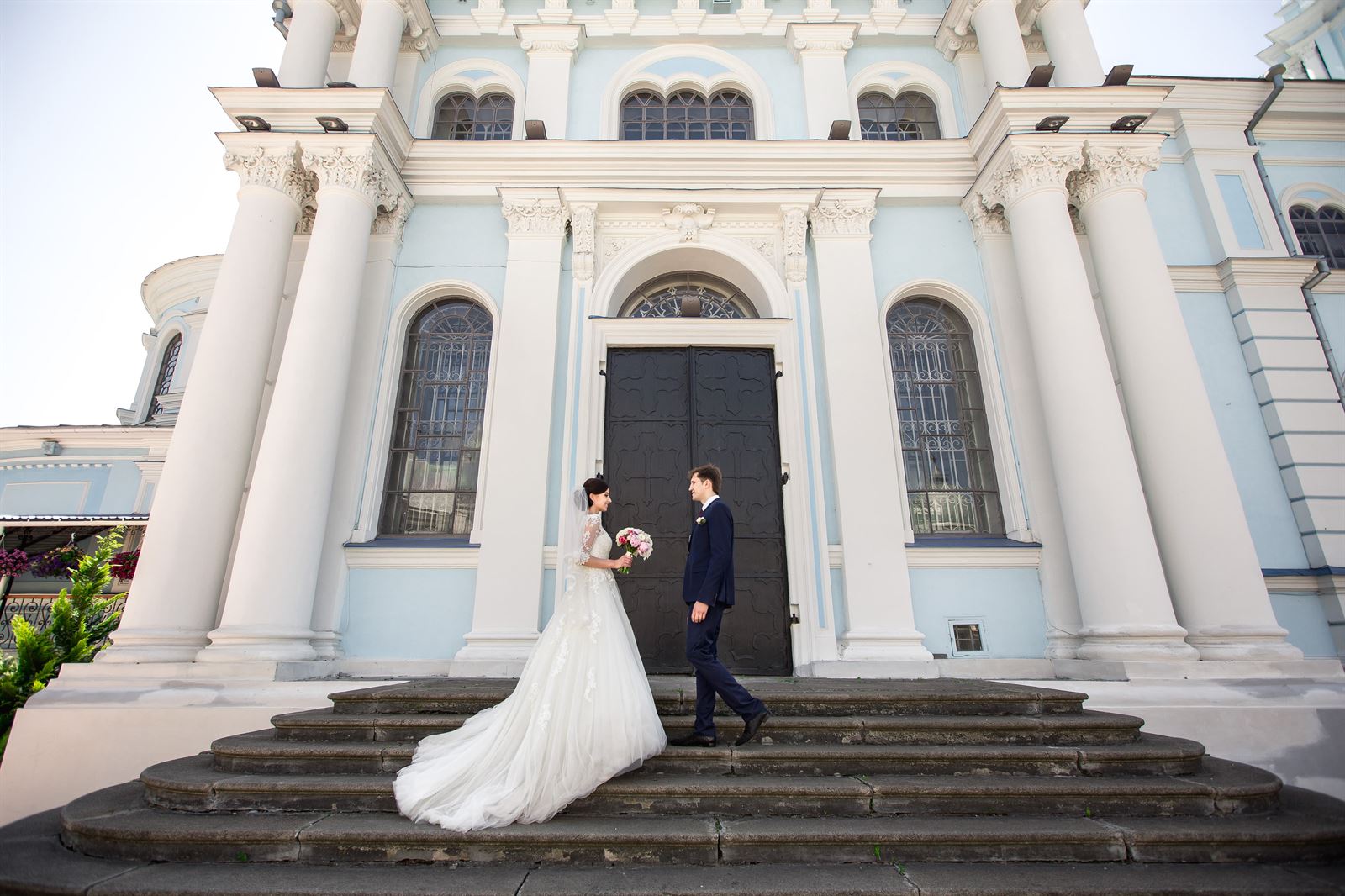 Braut und Bräutigam außerhalb einer blauen Hochzeitslocation