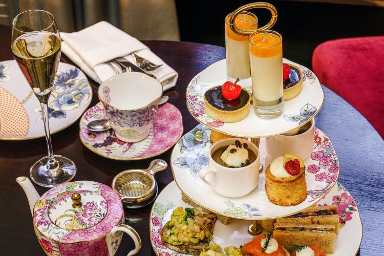 High tea with sandwiches and desserts served on china with flowers