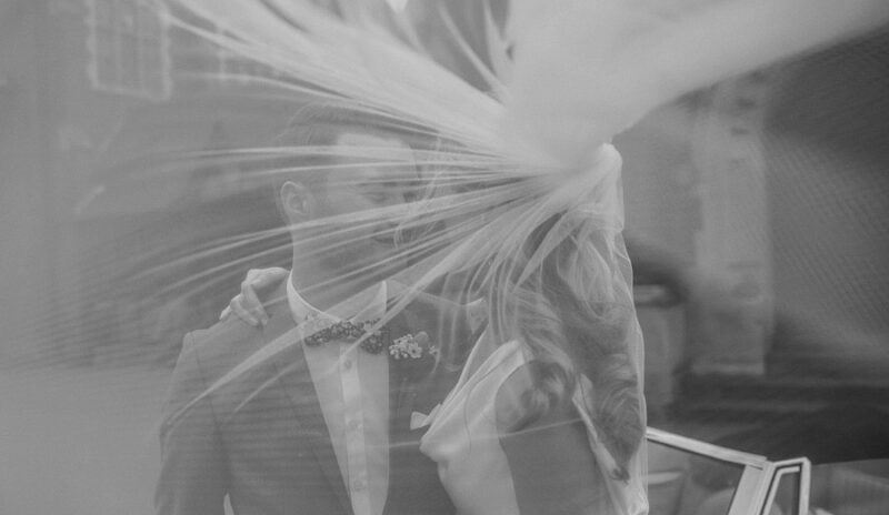 Bridebook.co.uk- bride and groom behind brides billowing veil