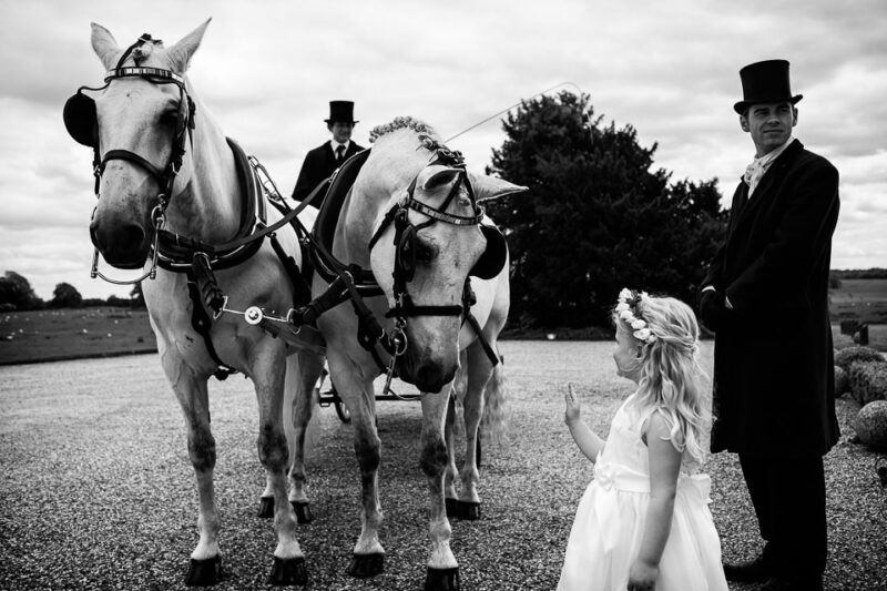 Bridebook.co.uk- flower girl waving up at the horse drawn carriage