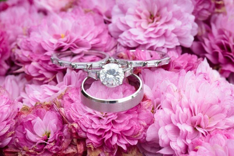 Bridebook.co.uk- wedding rings and engagement ring on top of pink flowers