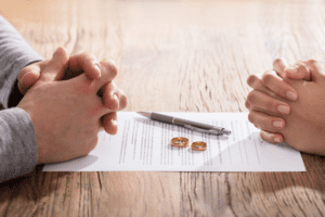 Couple signing a marriage contract with their wedding rings laid upon the document