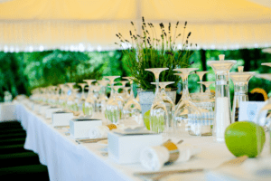 Long white table laid with wedding favours wrapped in white boxes and green apples