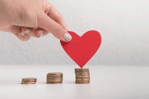 Piles of coins with a cut-out red paper heart