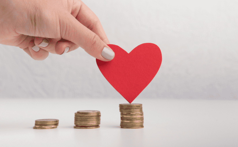 Piles of coins with a cut-out red paper heart