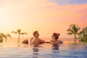 Bride and groom on romantic honeymoon overlooking the sunset in a luxurious infinity pool