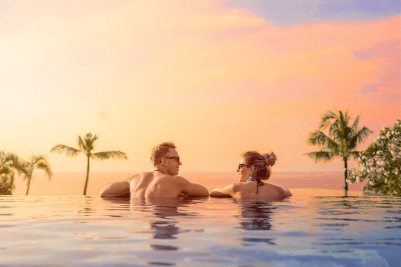 Bride and groom on romantic honeymoon overlooking the sunset in a luxurious infinity pool