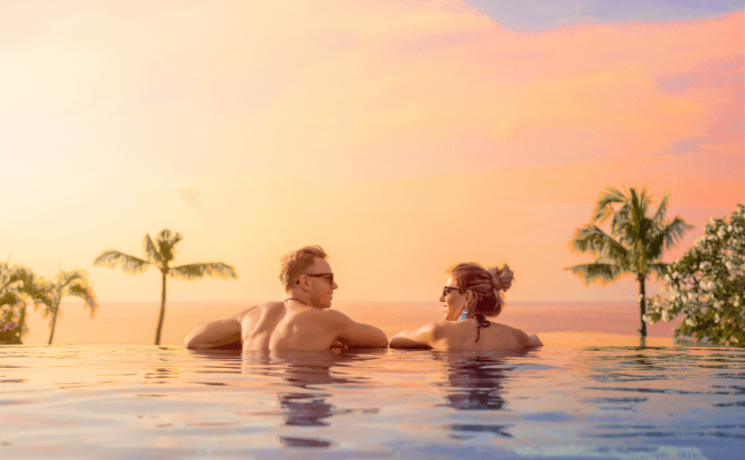 Bride and groom on romantic honeymoon overlooking the sunset in a luxurious infinity pool