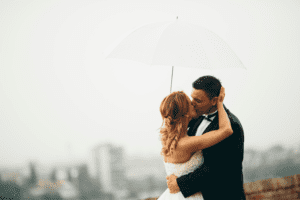Bride and groom under umbrella rainy day wedding