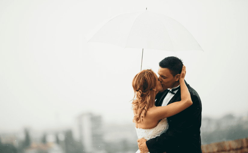 Bride and groom under umbrella rainy day wedding