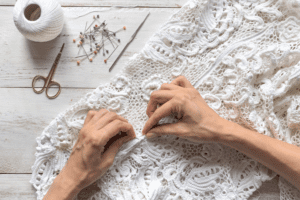 Hands sewing an old wedding dress