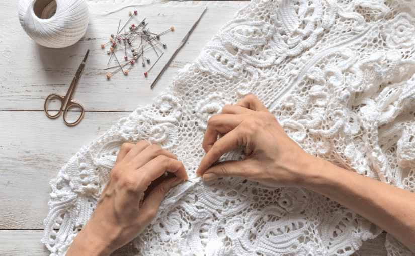 Hands sewing an old wedding dress