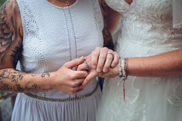 Two brides holding hands to reveal diamond engagement ring on one of their fingers