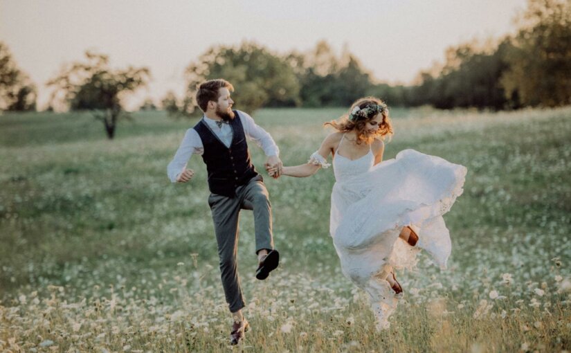 Young married couple running in a field