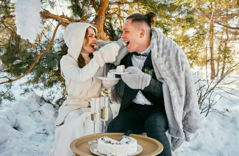 Couple eating a wedding cake in a winter landscape