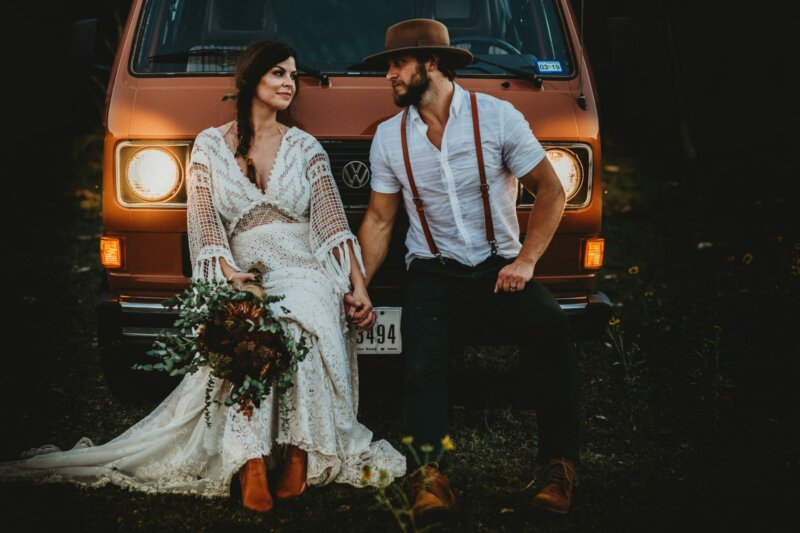 Newly weds laying on a car with a bouquet