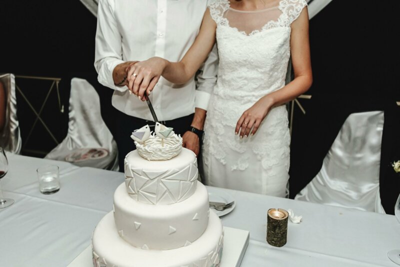 Couple cutting a wedding cake with bird topper