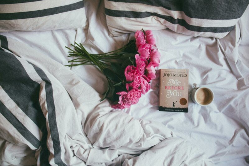 Bouquet de fleurs, livre et café sur un lit