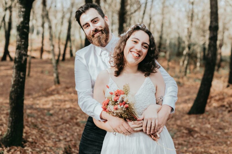 Newly weds with a small natural bouquet in a forest