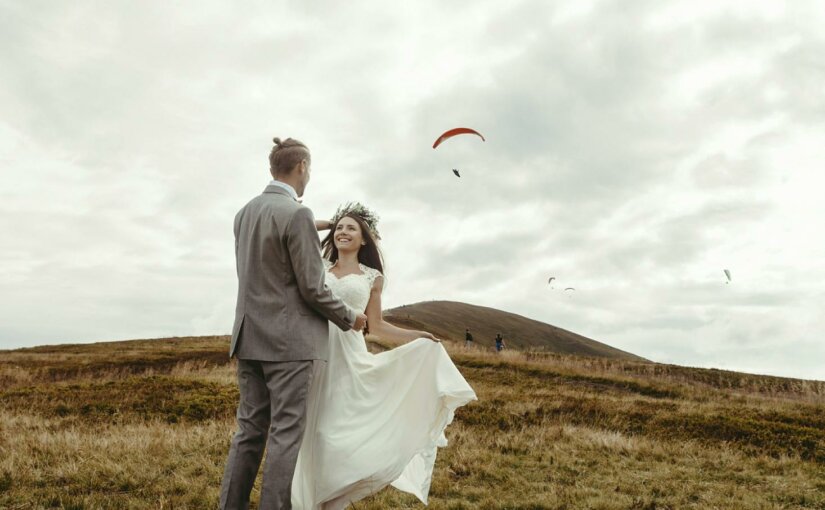 Mariés dans un champs avec un parapente