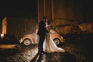 Married couple in front of a vintage car at night