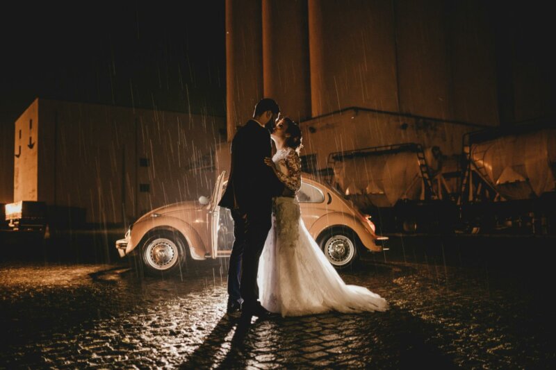 Married couple in front of a vintage car at night
