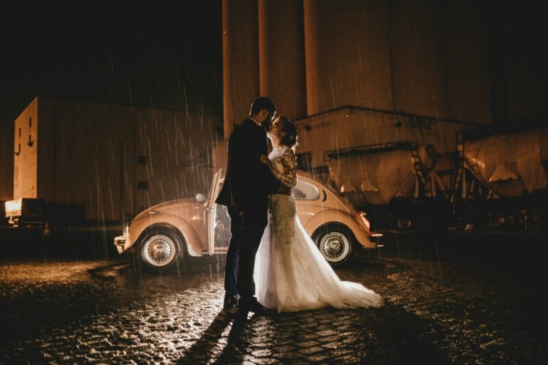 Married couple kissing in front of a vintage car