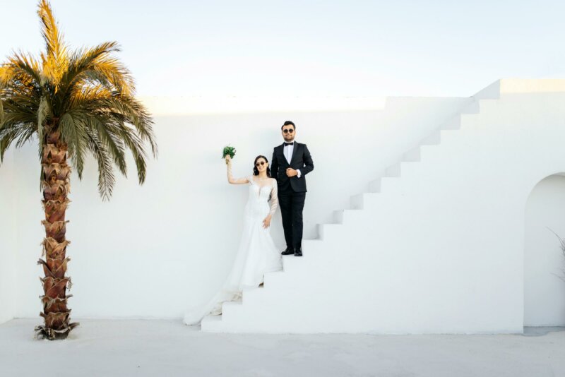 Married couple standing on white stairs next to a palmtree