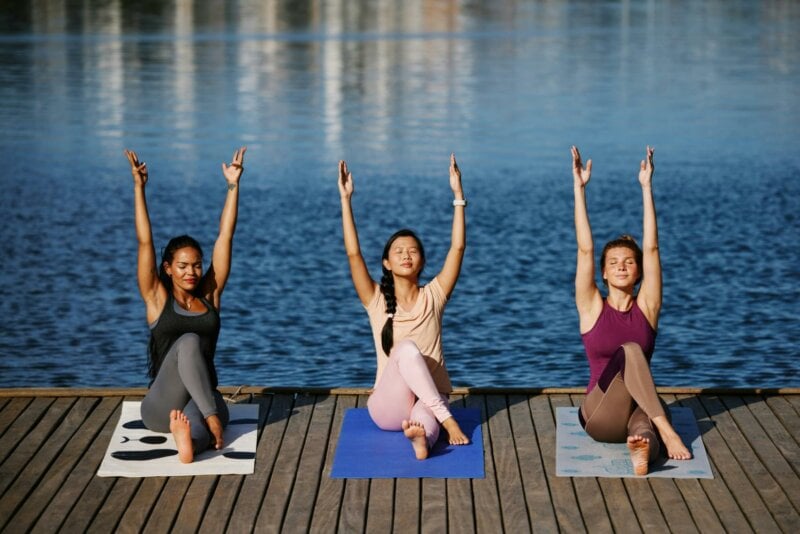 Three women doing yoga by the sea