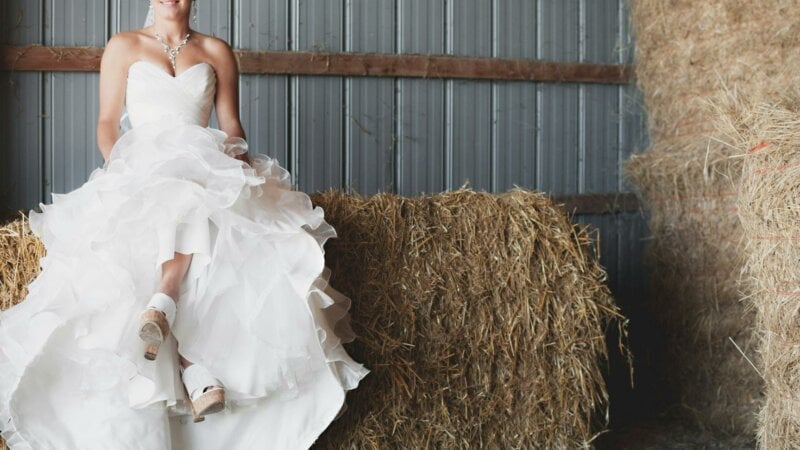 Bride sitting on hay with a voluminous wedding dress